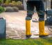 Cleaning a Patio With a Pressure Washer While Wearing Yellow Waterproof Boots in the Garden