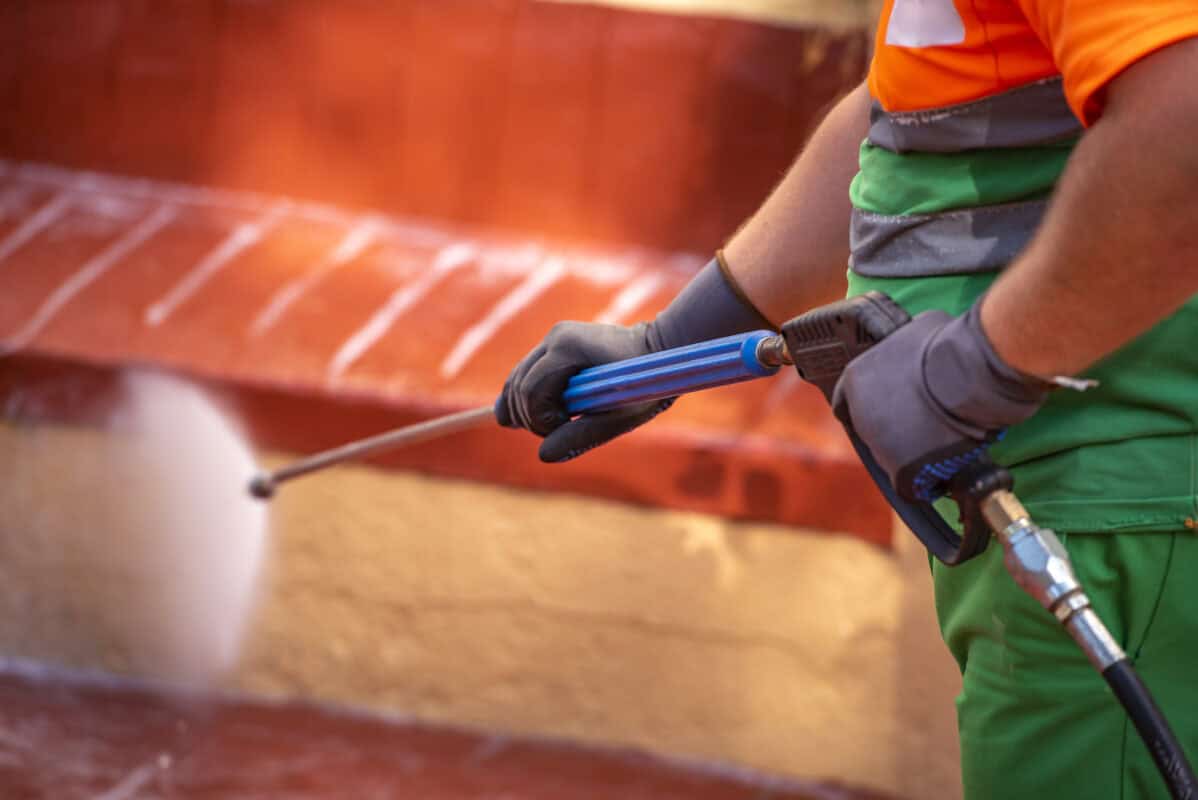 Worker cleaning the streets with a pressurized bleach water gun